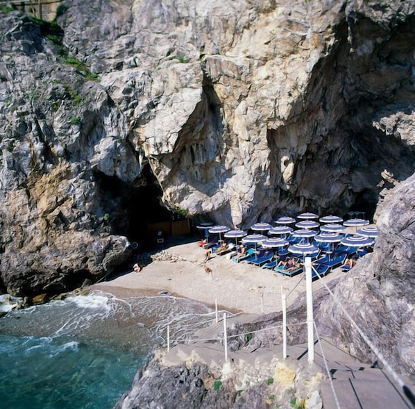 A rocky coastal area with a beach and umbrellas. - Hotel Club Due Torri (Maiori)