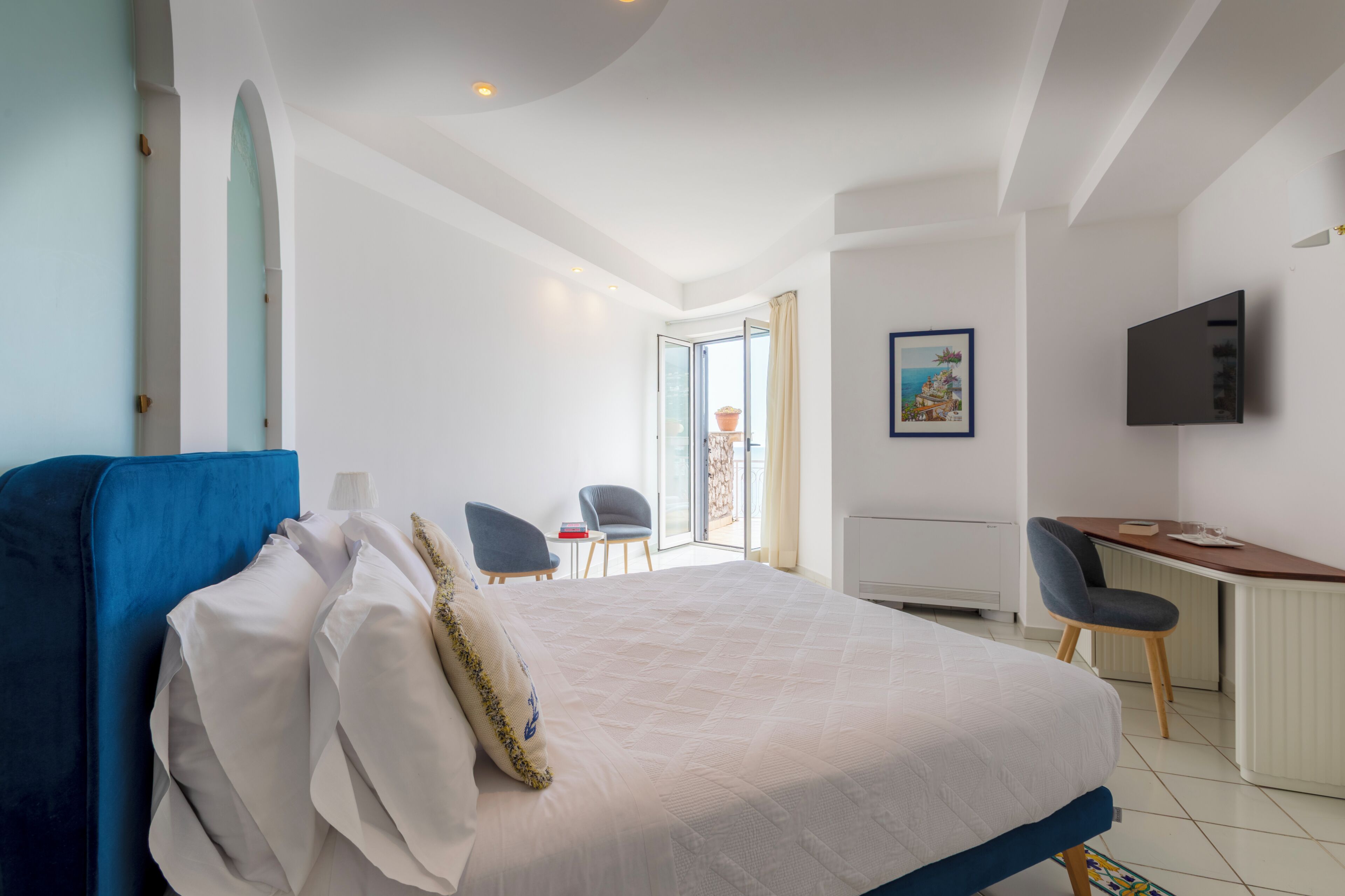 Ein Hotelzimmer mit Bett, Schreibtisch, Fernseher und Blick ins Freie.