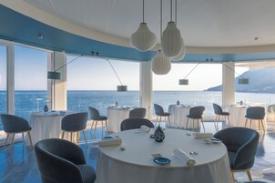 A modern dining area with round tables, chairs, and hanging pendant lights.