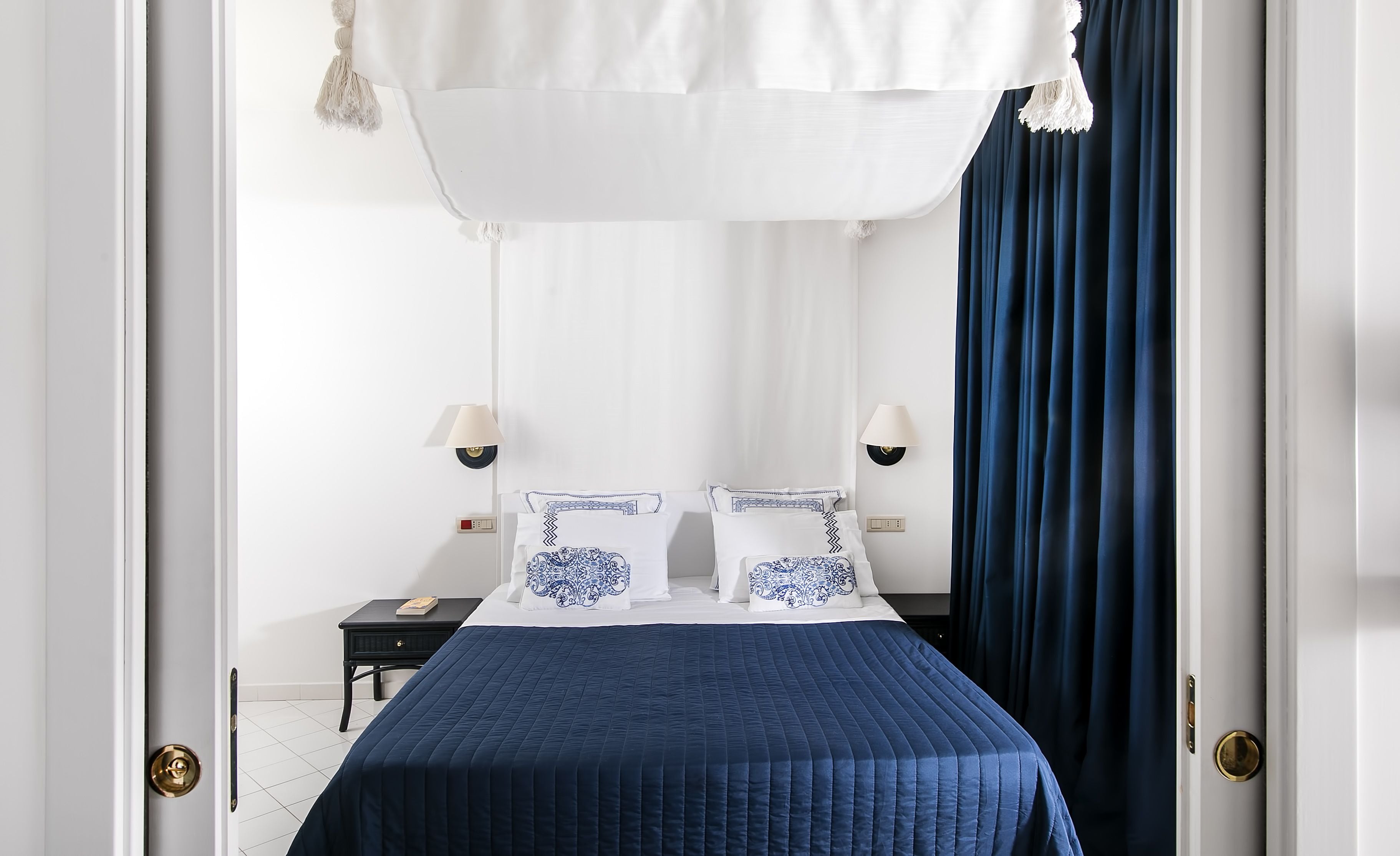 Quarto bem organizado com uma cama, duas mesas de cabeceira e um dossel.