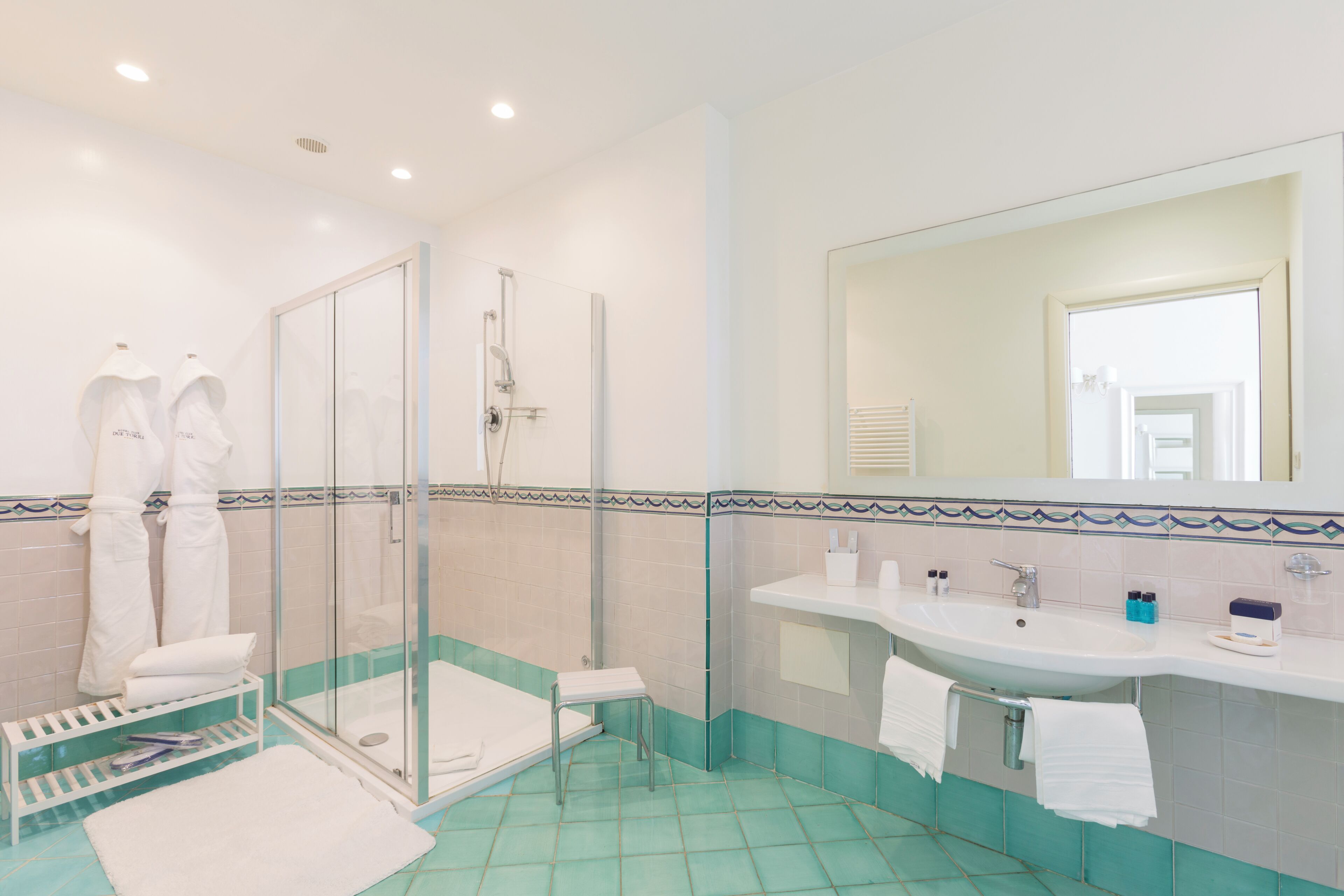 A bathroom with a glass shower enclosure, a sink with toiletries, and a mirror.