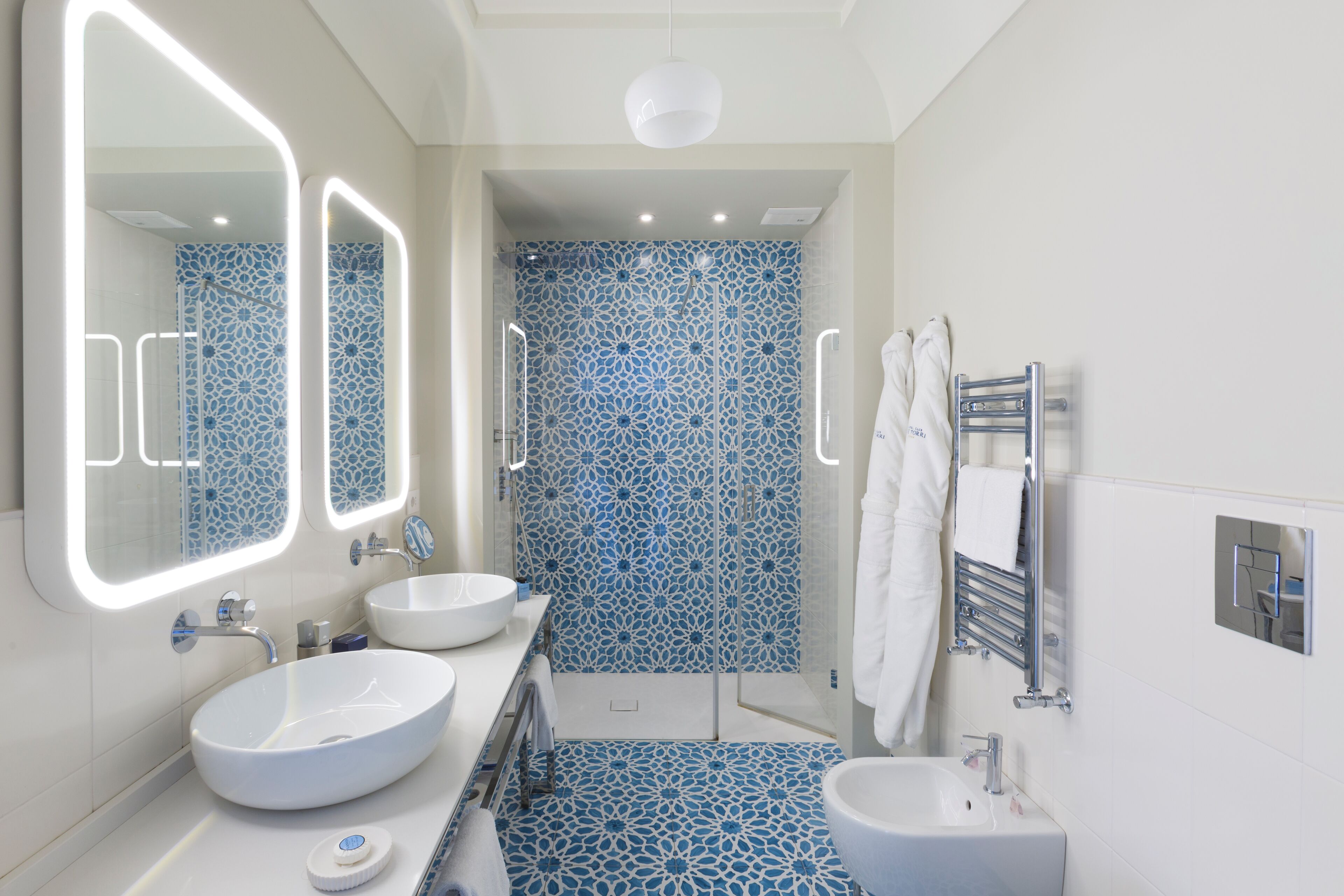 A modern bathroom with two sinks, a shower, and a toilet.