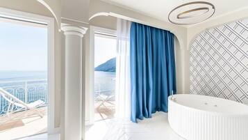 Une salle de bain luxueuse avec une grande baignoire, une vue sur la mer et un mur décoré de motifs.