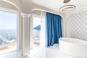 Une salle de bain luxueuse avec une grande baignoire, une vue sur la mer et un mur décoré de motifs.