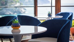 A table with a potted plant, blue chairs, and a view of the ocean. - Palazzo Vingius (Minori)