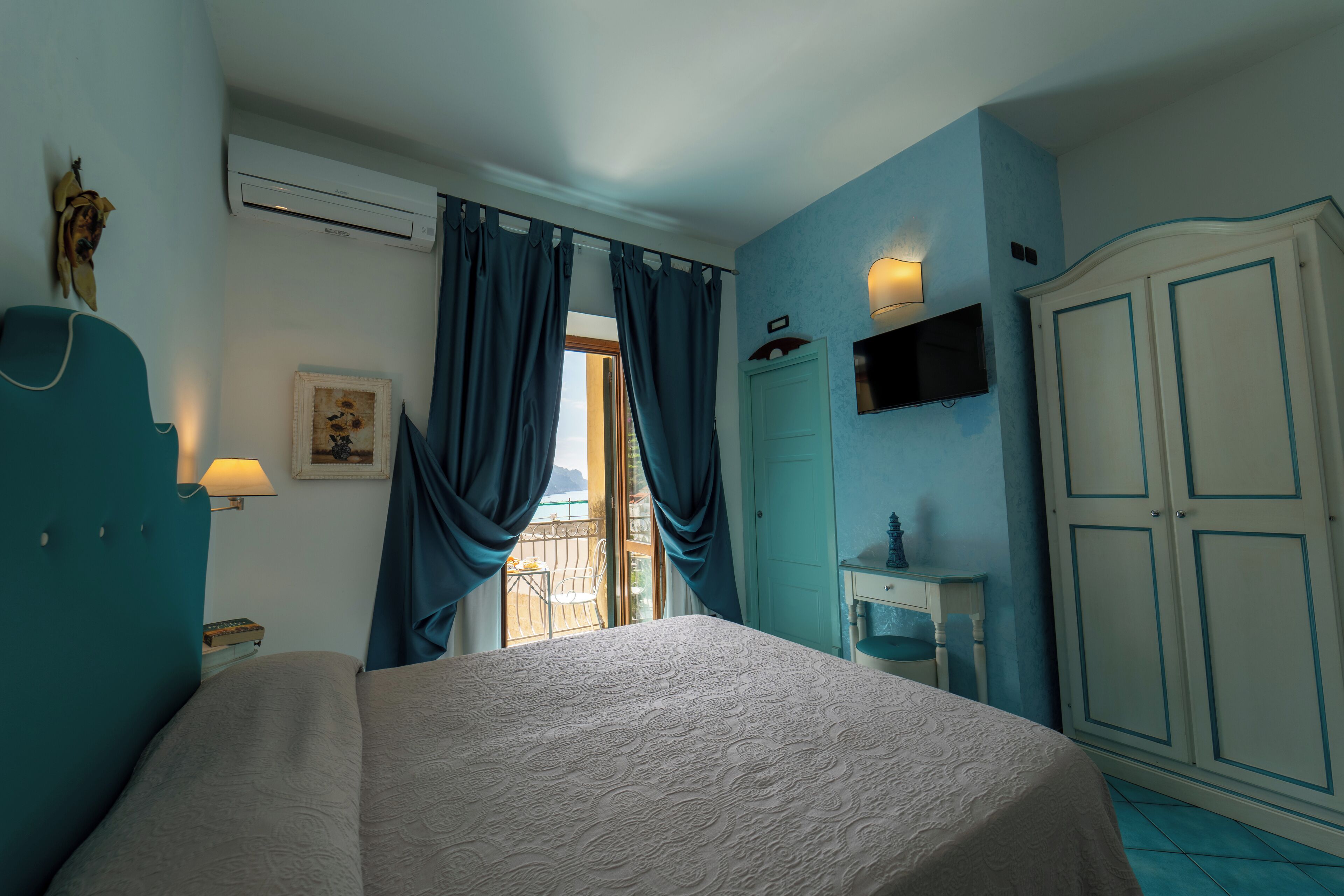 A bedroom with a bed, a wardrobe, a desk, and a window with curtains.