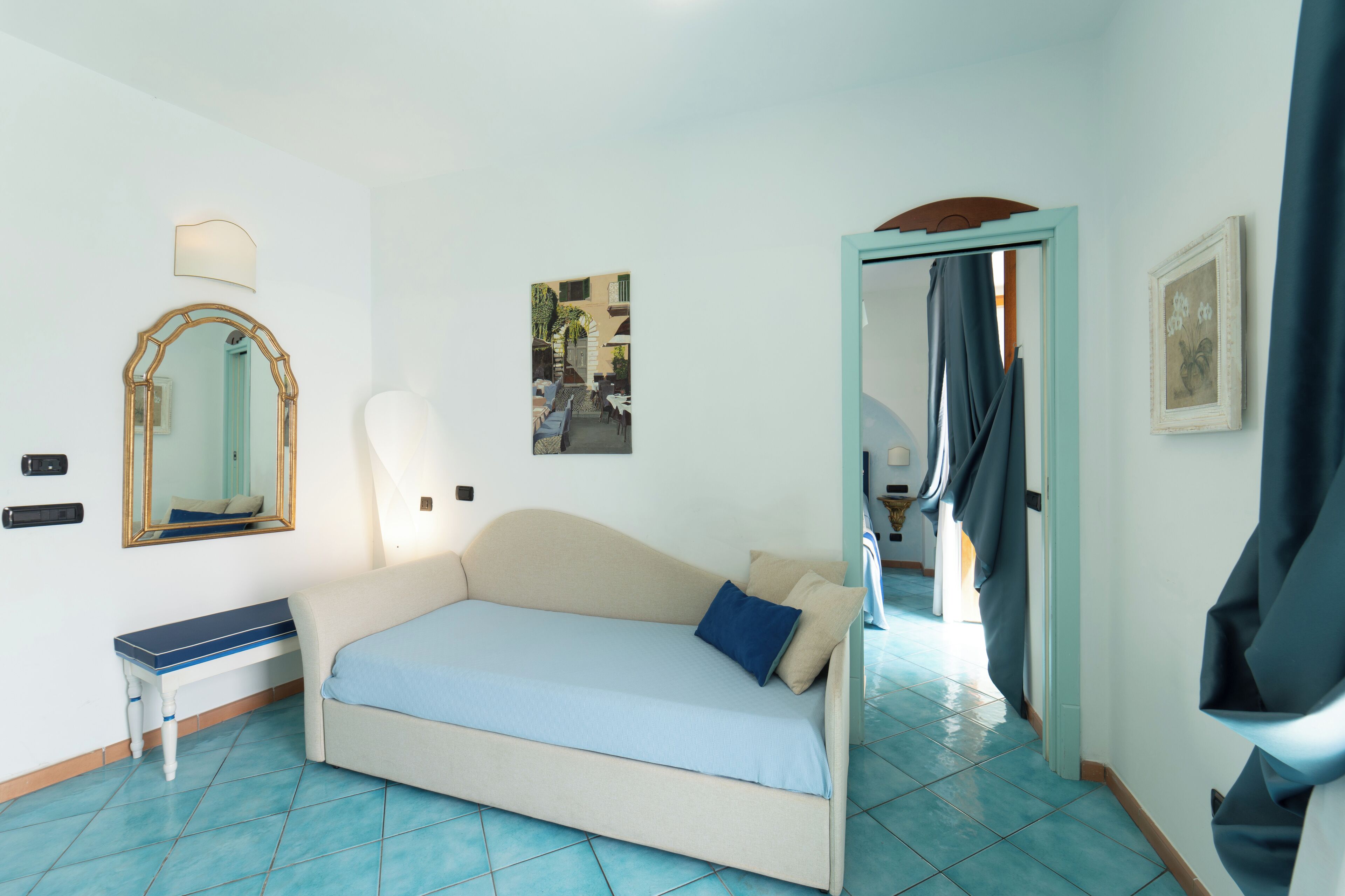 Une chambre à coucher comprenant un lit, une table de chevet, un miroir et une porte donnant sur une autre pièce.