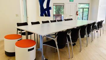 A conference room with a long table, black chairs, and two orange stools.