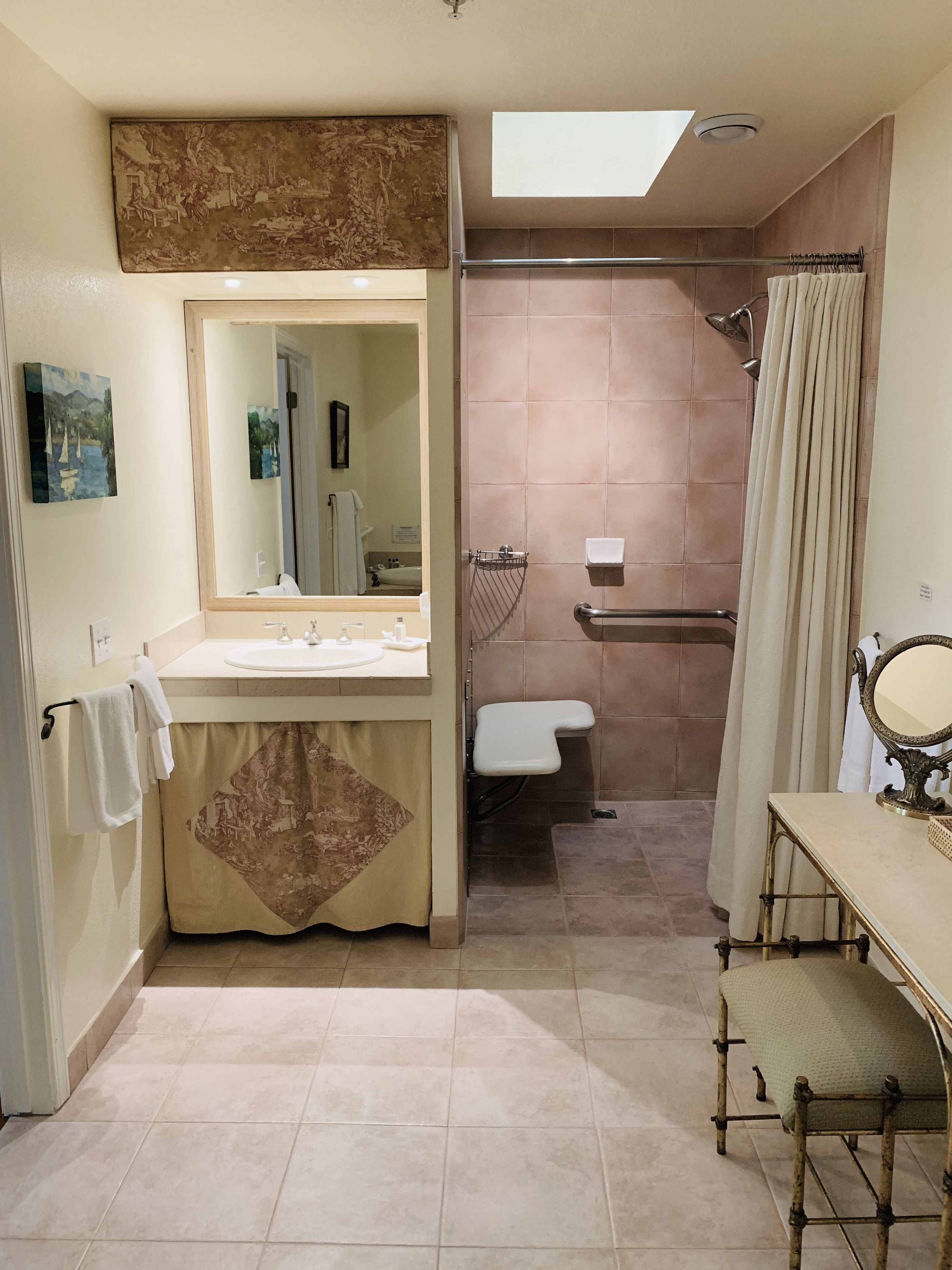 A bathroom with a shower, toilet, sink, and a vanity with a mirror.