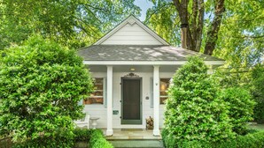 A white building with a dark door, surrounded by lush greenery. - Cottage Grove Inn (Calistoga)