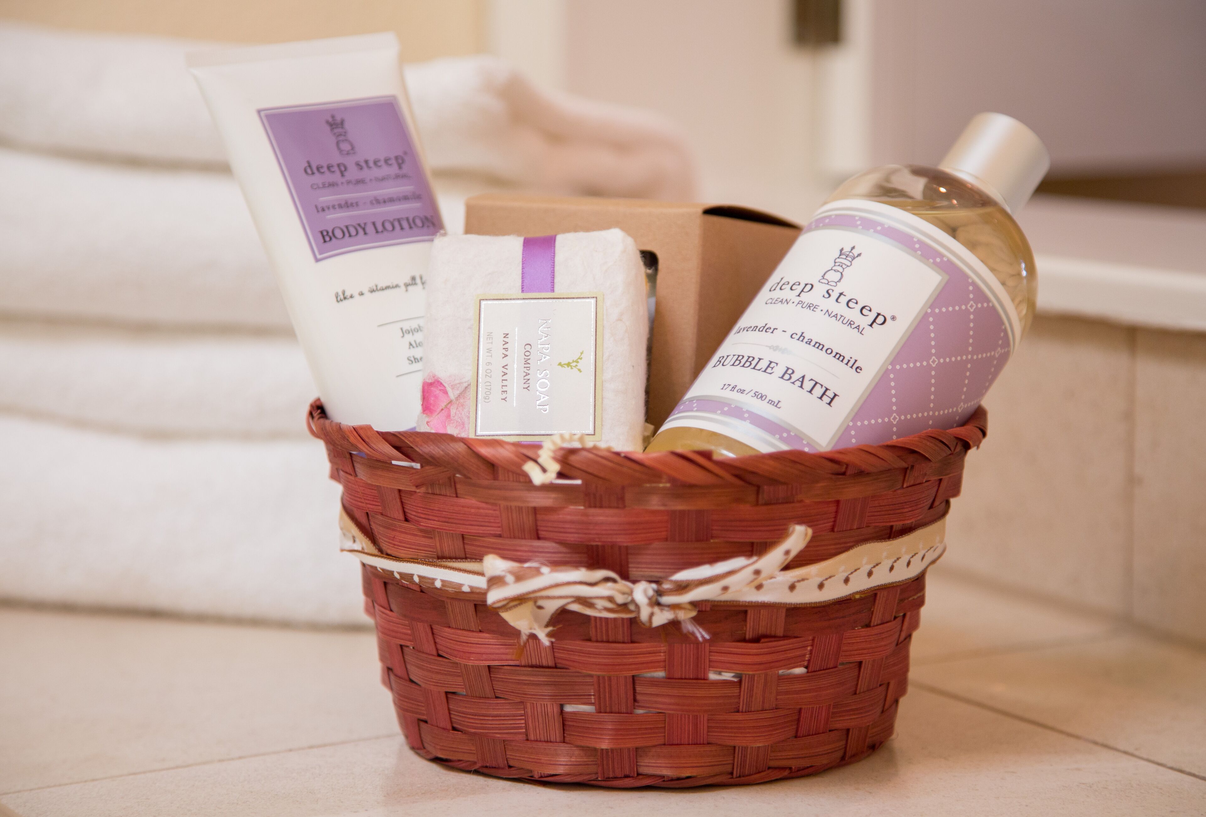 Una cesta de mimbre con una botella de loción corporal, una pastilla de jabón y una caja de productos de baño.