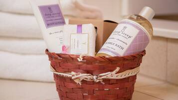 Una cesta de mimbre con una botella de loción corporal, una pastilla de jabón y una caja de productos de baño.