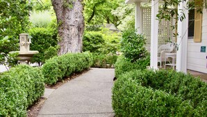 A pathway leading to a building with a white exterior and a covered porch area. - Cottage Grove Inn (Calistoga)