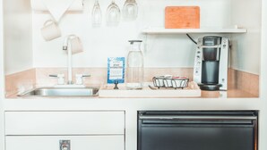 A kitchen with a coffee maker, a kettle, a water dispenser, and a wooden cutting board on the counter. - Cottage Grove Inn (Calistoga)