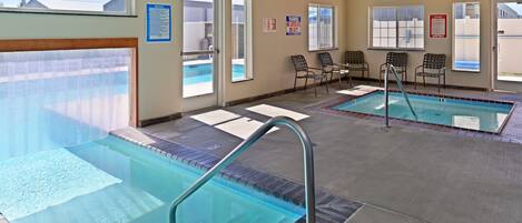 Uma área de piscina com duas piscinas, cadeiras e placas de segurança.