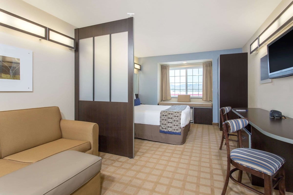Una habitación de hotel con una cama, un sofá, un escritorio y una televisión.