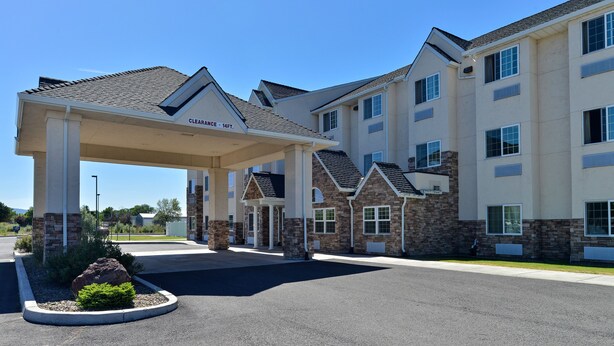 A hotel entrance with a covered parking area, stone facade, and multiple windows.