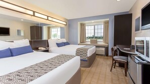 A hotel room with two beds, a desk, a chair, a TV, and a minibar.