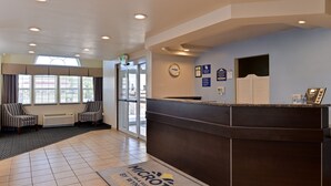 A reception area with a dark reception desk, two striped chairs, a clock, and a door leading outside.