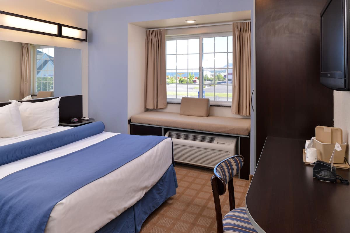 Habitación de hotel con dos camas, televisión, ventana con cortinas y vistas al exterior.