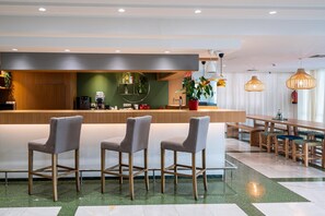 Un espace bar moderne comprenant un comptoir, des tabourets de bar et une table à manger avec des bancs.