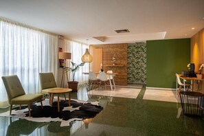 A modern living room with a glass coffee table, two armchairs, a wooden sideboard, and a green accent wall. - Hotel THB Niagara - Adults Only (Palma de Mallorca)