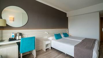 Una habitación de hotel con cama, escritorio, silla, espejo y mesita de noche.