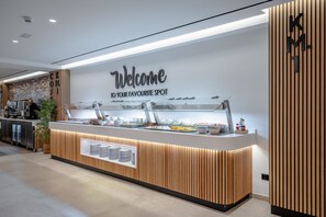 A modern reception area with a 'Welcome to your favourite spot' sign, a buffet counter with various food items, and a wooden panel design on the walls. - Hotel THB Niagara - Adults Only (Palma de Mallorca)