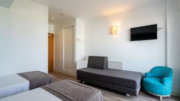 Una habitación de hotel con dos camas, un sofá, un televisor y una silla.