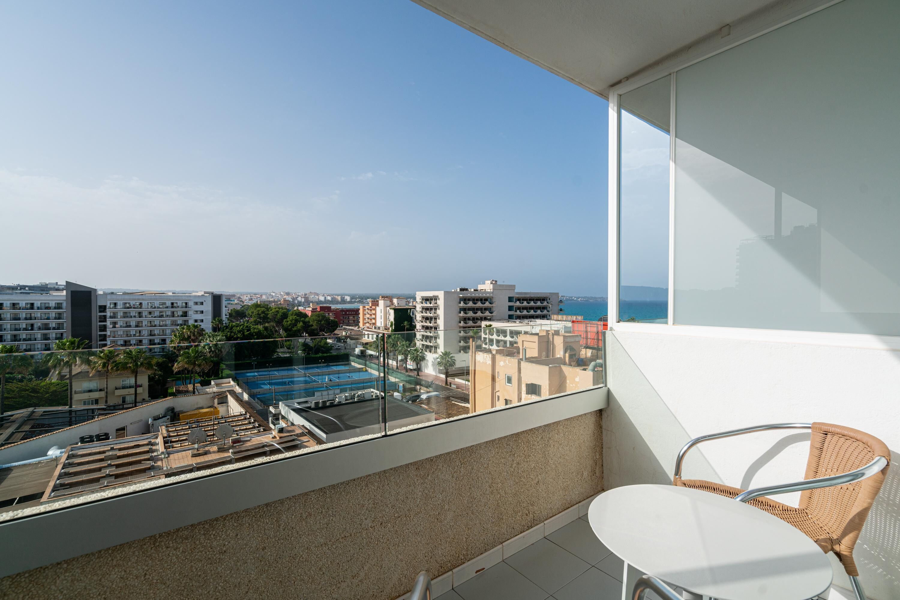 Un balcón con vista a una piscina, edificios y el mar.
