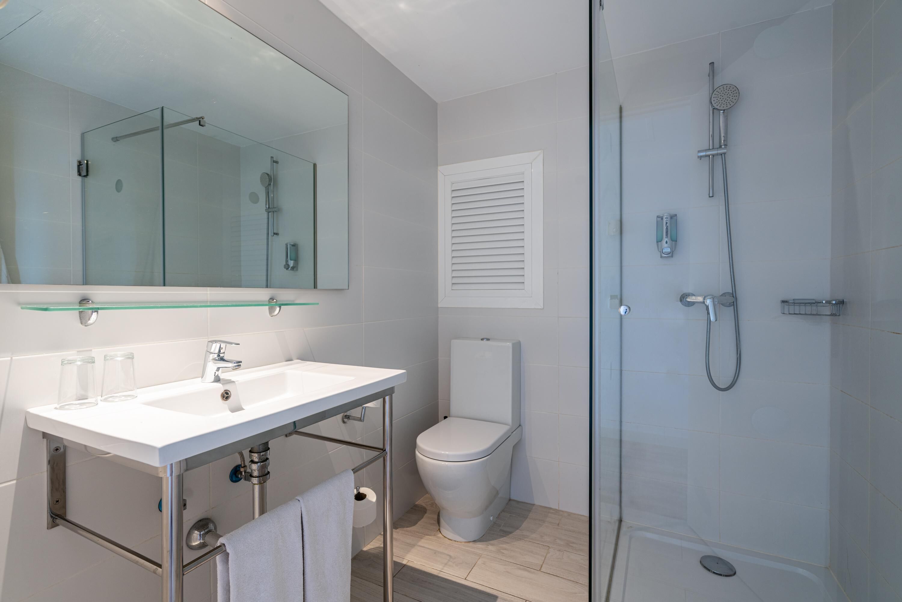 A modern bathroom with a glass shower enclosure, a white sink with a mirror, and a toilet.