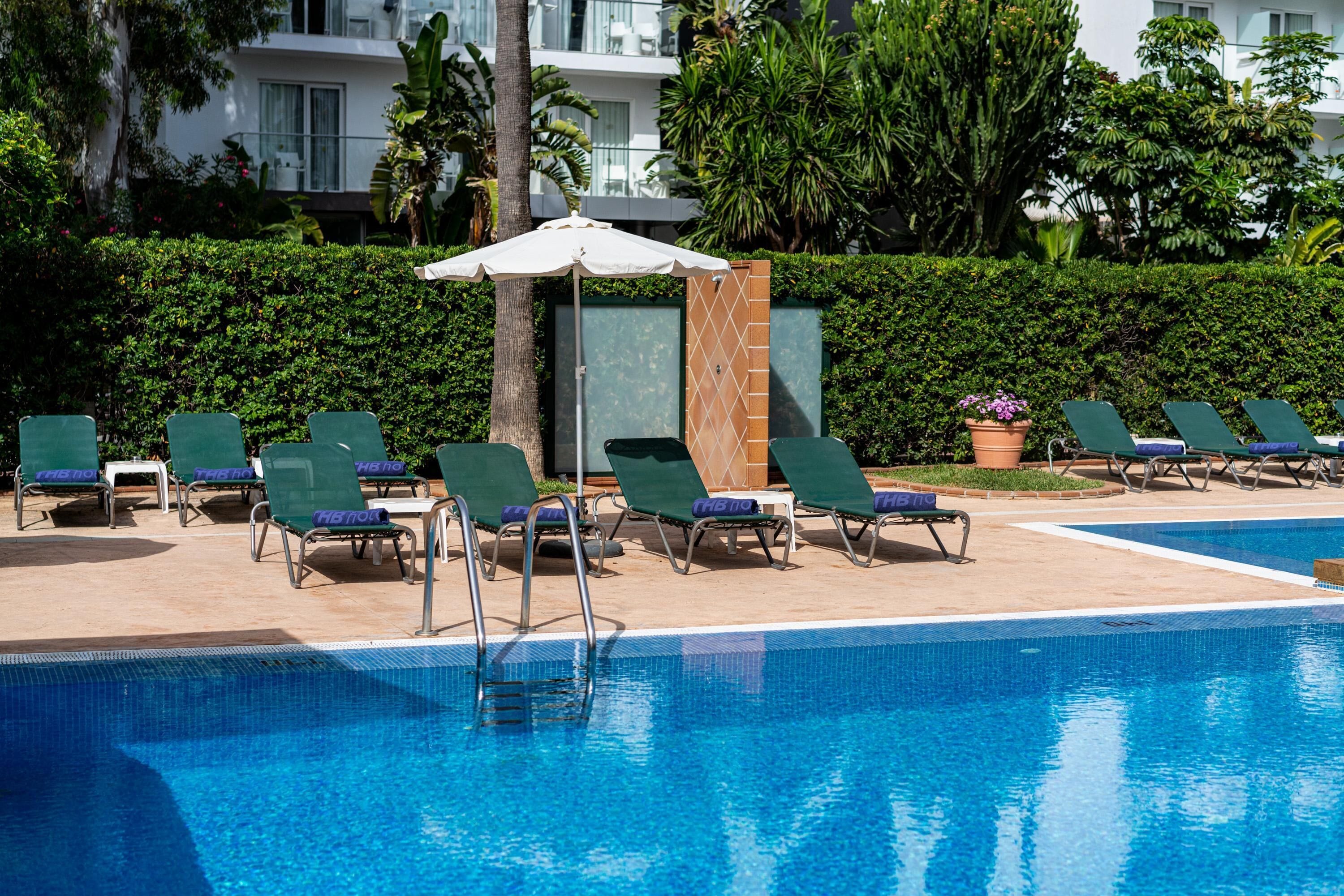 Une piscine avec des chaises longues et un parasol.
