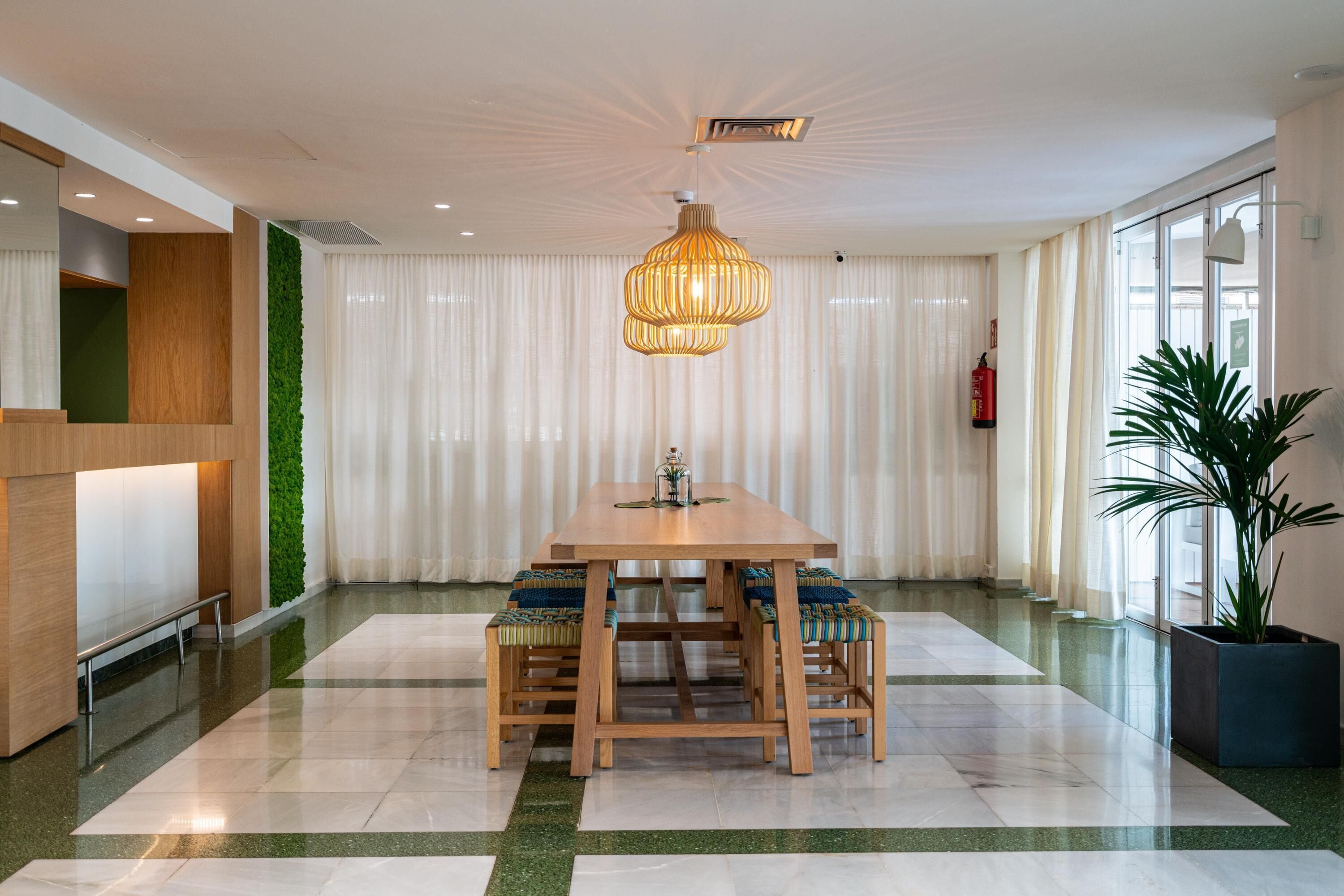 Un comedor moderno con una mesa y sillas de madera, una lámpara colgante y una pared verde.