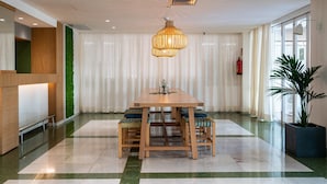 A modern dining area with a wooden table and chairs, a hanging light fixture, and a green wall. - Hotel THB Niagara - Adults Only (Palma de Mallorca)