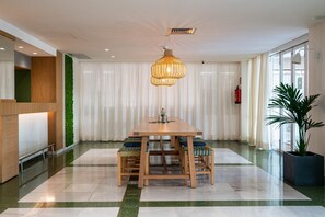 A modern dining area with a wooden table and chairs, a hanging light fixture, and a green wall. - Hotel THB Niagara - Adults Only (Palma de Mallorca)