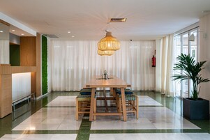 Un comedor moderno con una mesa y sillas de madera, una lámpara colgante y una pared verde.