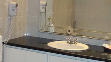 A bathroom with a white sink, a mirror, a towel rack, and a toilet paper holder.