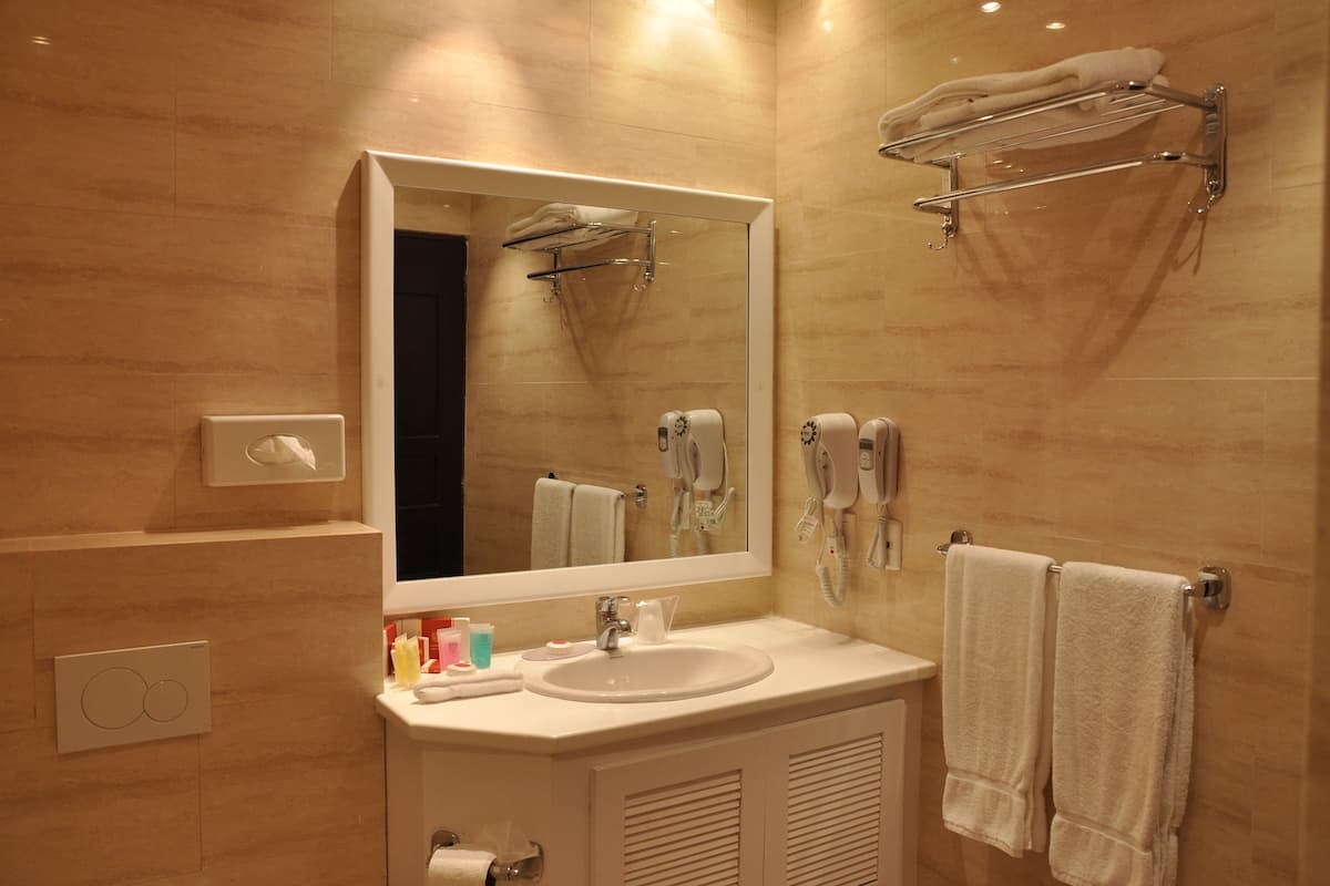 Een moderne badkamer met een grote spiegel, een wastafel en twee handdoekrekken.
