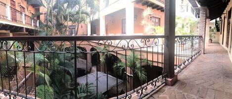 A balcony with wrought iron railings, potted plants, and a tiled floor.