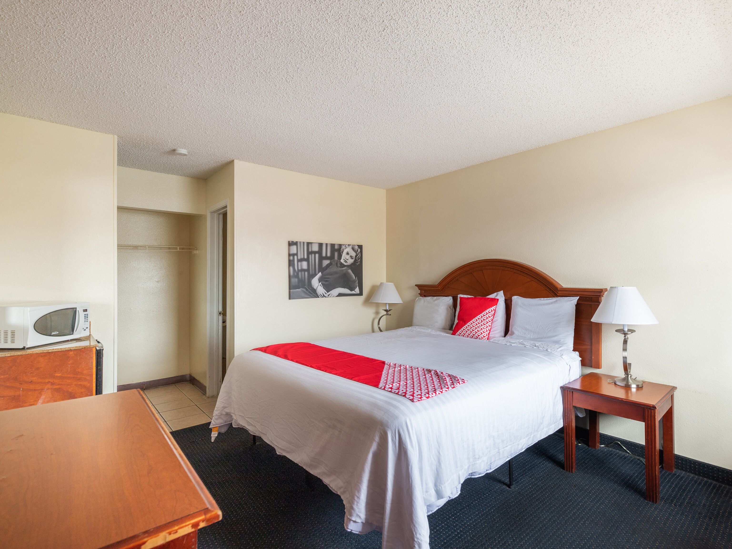 Habitación de hotel con cama, mesitas de noche, microondas y puerta.