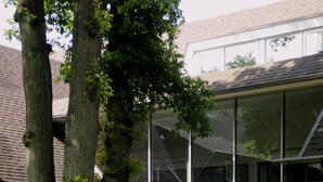 A modern building with large glass windows, a grassy lawn, and trees. - Van der Valk Hotel Hilversum - de Witte Bergen (Eemnes)