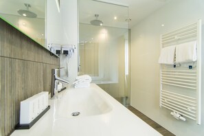A modern bathroom with a large sink, a mirror, a towel rack, and a shower area. - Van der Valk Hotel Hilversum - de Witte Bergen (Eemnes)