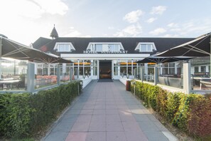 A hotel restaurant with a covered entrance, glass walls, and a clear pathway leading to the entrance. - Van der Valk Hotel Hilversum - de Witte Bergen (Eemnes)