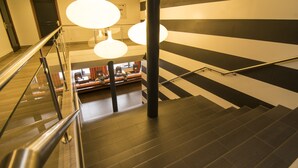 A staircase with a handrail, a black and white striped wall, and a seating area with a view. - Van der Valk Hotel Hilversum - de Witte Bergen (Eemnes)