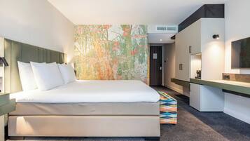 Une chambre d’hôtel moderne équipée d’un lit, d’un bureau et d’une grande œuvre d’art abstraite accrochée au mur.