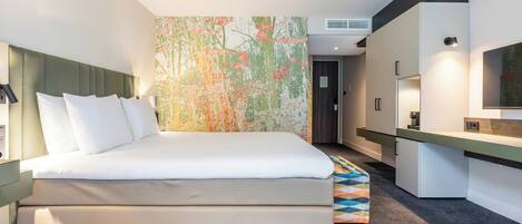 A modern hotel room with a bed, a desk, and a large abstract wall art piece.