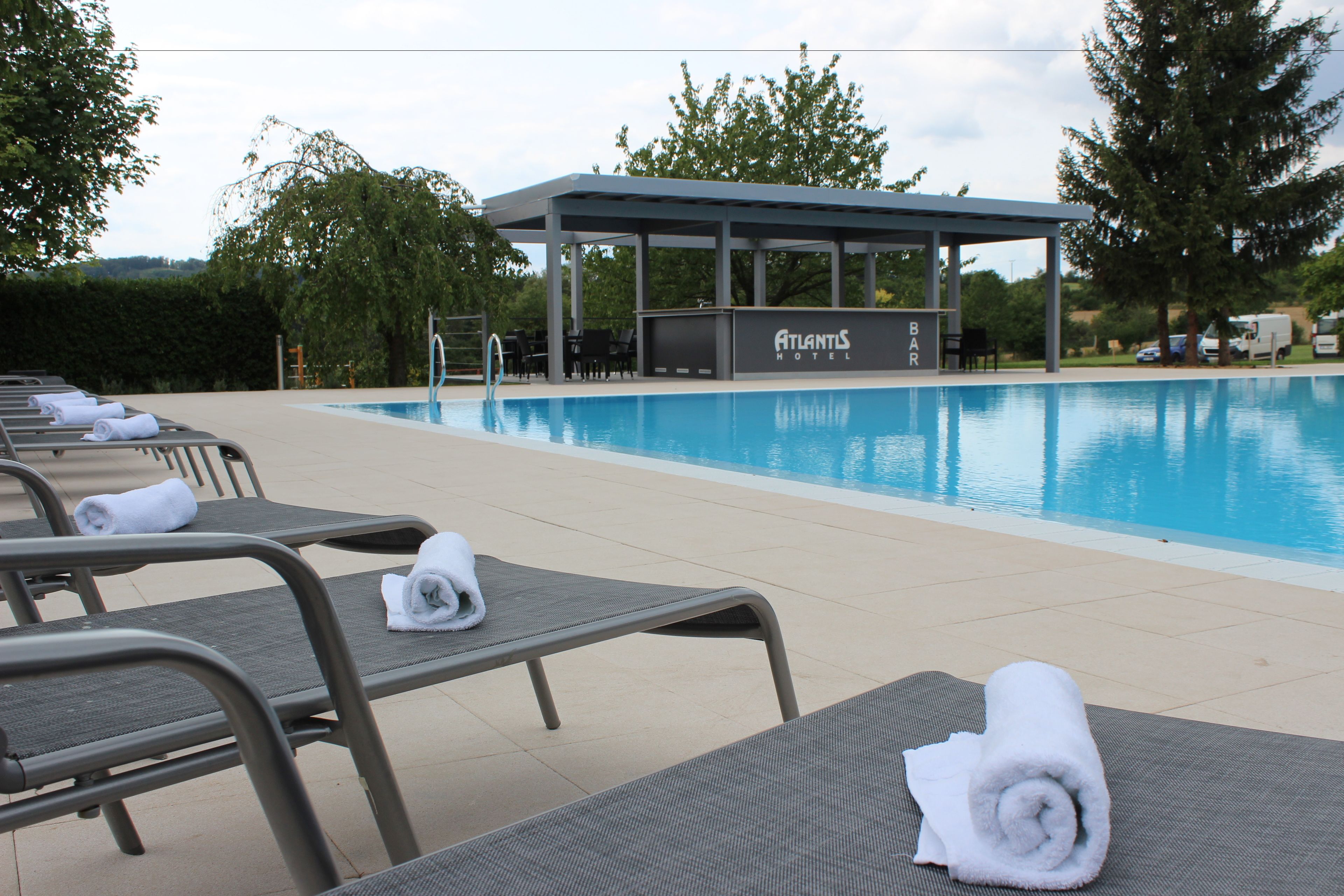 A poolside area with lounge chairs and a covered seating area at Atlantis Hotel.