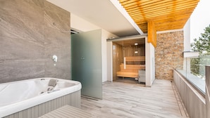 Une salle de bain moderne avec une grande baignoire, un banc en bois et un mur en pierre.