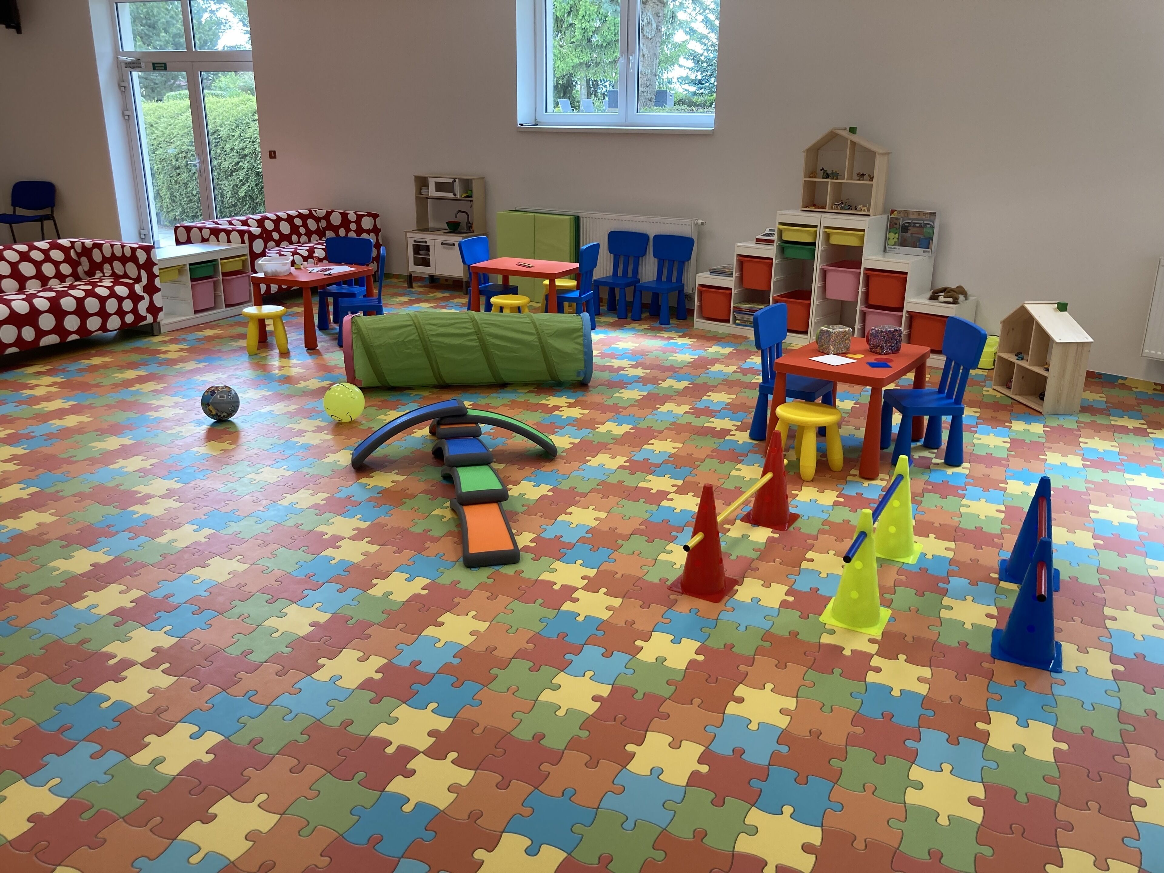 Un cuarto de juegos con tapetes de puzzle de colores, muebles infantiles y unidades de almacenamiento.