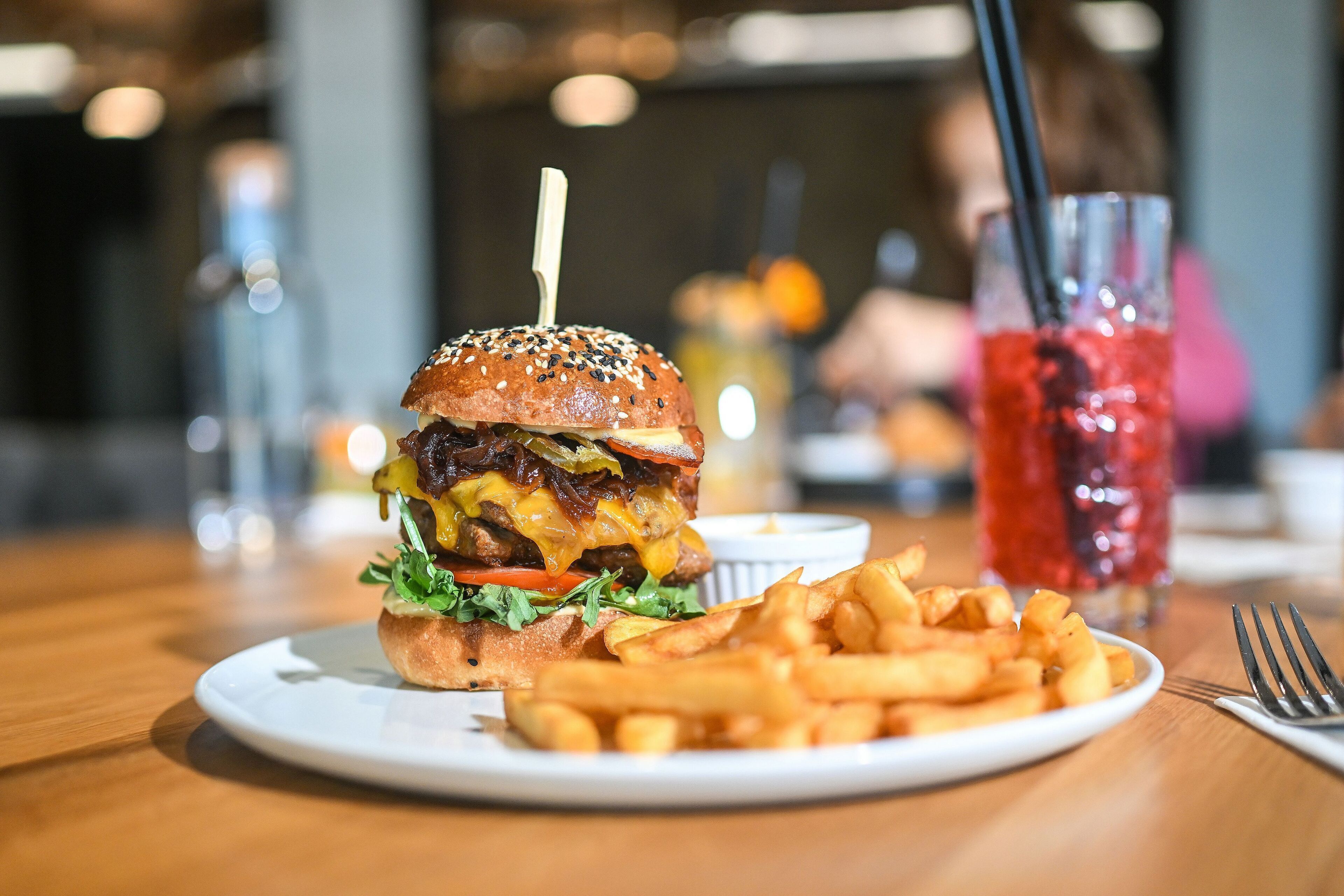 A burger with fries and a drink on a table.